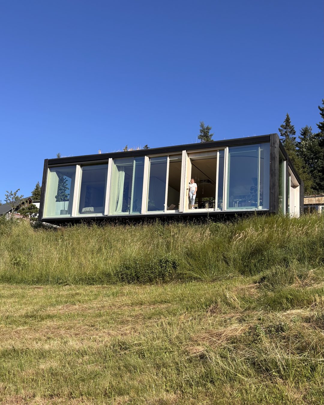 Atelier House seen from the meadow, under a blue sky